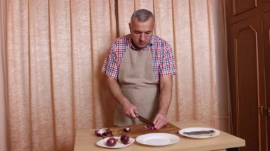 Bir adam soğanlı ringa balığı pişiriyor. Ev yemeği..