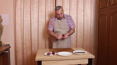 Bir adam soğanlı ringa balığı pişiriyor. Ev yemeği..