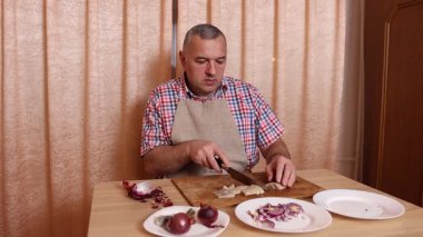 Bir adam soğanlı ringa balığı pişiriyor. Ev yemeği..