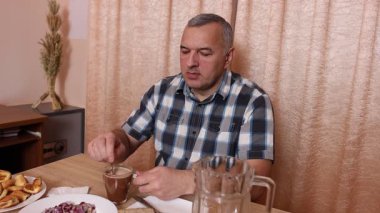 Adam masada otururken yemek ve içki yiyor. Ev yemekleri..