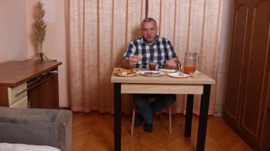 Adam masada otururken yemek ve içki yiyor. Ev yemekleri..