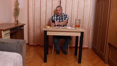 Adam masada otururken yemek ve içki yiyor. Ev yemekleri..