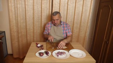 Bir adam soğanlı ringa balığı pişiriyor. Ev yemeği..