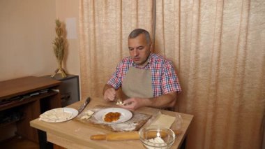Bir adam hamurdan ve tatlı dolgudan turtalar hazırlar. Ev yapımı yemekler..