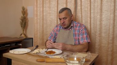 Bir adam hamurdan ve tatlı dolgudan turtalar hazırlar. Ev yapımı yemekler..