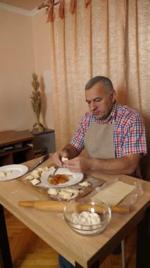 Bir adam hamurdan ve tatlı dolgudan turtalar hazırlar. Ev yapımı yemekler..