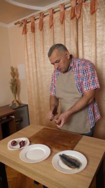 Bir adam soğanlı ringa balığı pişiriyor. Ev yemeği..