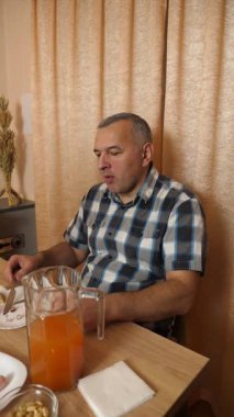 Adam masada otururken yemek ve içki yiyor. Ev yemekleri..