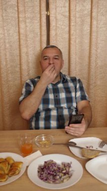 Adam masada otururken yemek ve içki yiyor. Ev yemekleri..