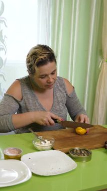 Bir kadın ezmeli, peynirli, lahanalı ve limonlu sandviç yapıyor..