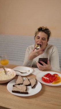 Bir kadın mutfaktaki masada otururken yemek ve içki yer..