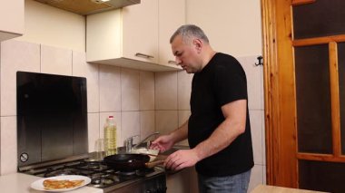 Bir adam tavada krep pişirir. Krep pişiriyorum..