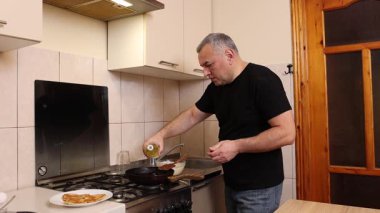 Bir adam tavada krep pişirir. Krep pişiriyorum..