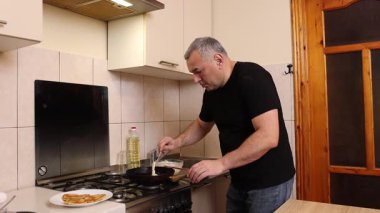 Bir adam tavada krep pişirir. Krep pişiriyorum..