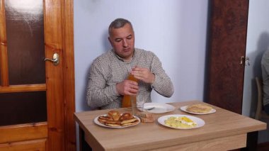 Bir adam masada otururken yemek ve içki yer..