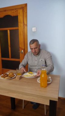 Bir adam masada otururken yemek ve içki yer..