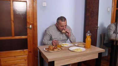 Bir adam masada otururken yemek ve içki yer..