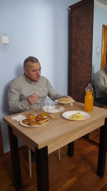 Bir adam masada otururken yemek ve içki yer..