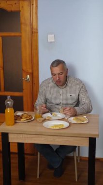 Bir adam masada otururken yemek ve içki yer..