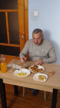 Bir adam masada otururken yemek ve içki yer..