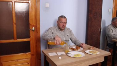 Bir adam masada otururken yemek ve içki yer..