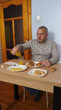 Bir adam masada otururken yemek ve içki yer..