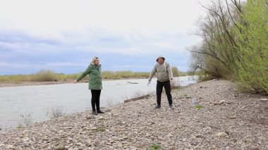 Bir erkek ve bir kadın nehir kenarında fiziksel egzersiz yapıyorlar..