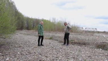 Bir erkek ve bir kadın nehir kenarında fiziksel egzersiz yapıyorlar..