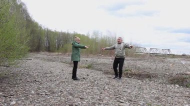 Bir erkek ve bir kadın nehir kenarında fiziksel egzersiz yapıyorlar..