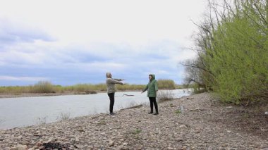 Bir erkek ve bir kadın nehir kenarında fiziksel egzersiz yapıyorlar..