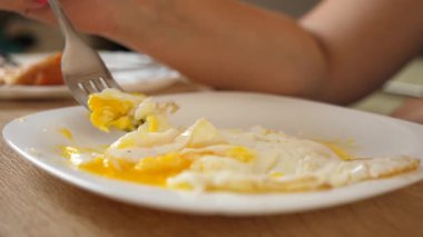 Kadın evdeki masada çırpılmış yumurta yiyor.