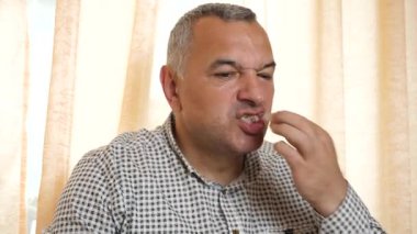 Bir adam evde masada otururken yemek yer..