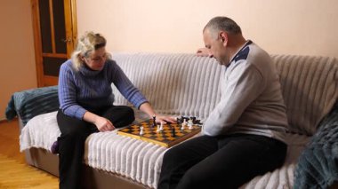 Kadın ve erkek kanepede satranç oynuyor..