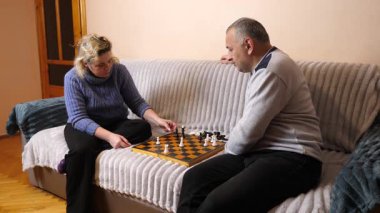 Kadın ve erkek kanepede satranç oynuyor..