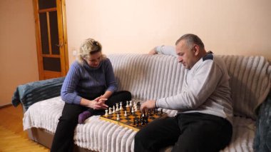 Kadın ve erkek kanepede satranç oynuyor..