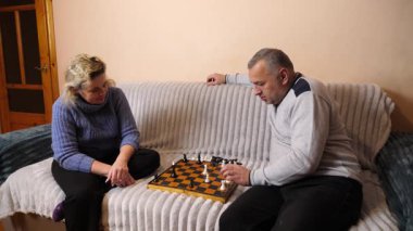 Kadın ve erkek kanepede satranç oynuyor..