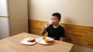 Bir adam masada otururken hamur işi yer, çay içer ve yoğurt içer..