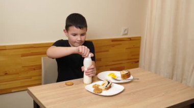 Bir adam masada otururken hamur işi yer, çay içer ve yoğurt içer..