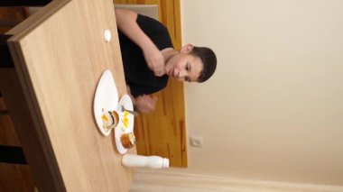 Bir adam masada otururken hamur işi yer, çay içer ve yoğurt içer..