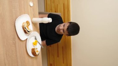 Bir adam masada otururken hamur işi yer, çay içer ve yoğurt içer..