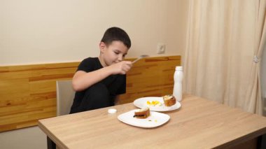 Bir adam masada otururken hamur işi yer, çay içer ve yoğurt içer..