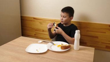 Bir adam masada otururken hamur işi yer, çay içer ve yoğurt içer..