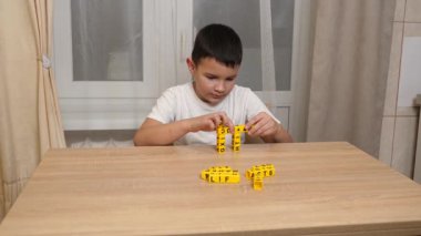 Bir çocuk masada otururken küplerden kelimeler üretiyor..