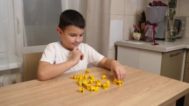 Bir çocuk masada otururken küplerden kelimeler üretiyor..