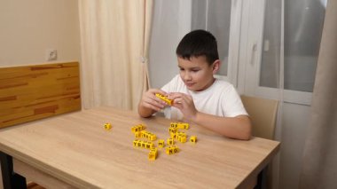 Bir çocuk masada otururken küplerden kelimeler üretiyor..