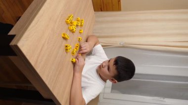 Bir çocuk masada otururken küplerden kelimeler üretiyor..