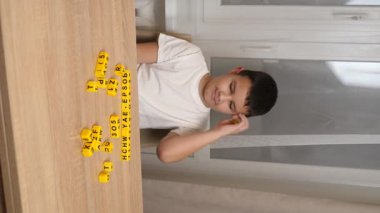 Bir çocuk masada otururken küplerden kelimeler üretiyor..