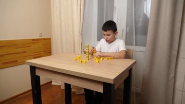 Bir çocuk masada otururken küplerden kelimeler üretiyor..