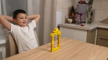 Bir çocuk masada otururken küplerden kelimeler üretiyor..