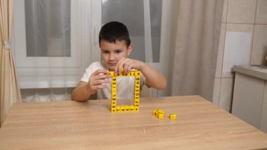 Bir çocuk masada otururken küplerden kelimeler üretiyor..